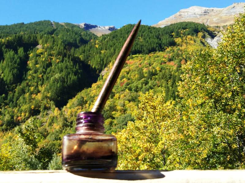 Un encrier et une plume illustrent l'article Bien écrire. En arrière-plan, la montagne en automne.